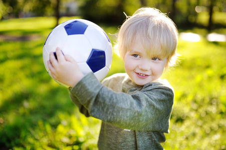 小男孩在阳光灿烂的夏天一天玩足球游戏的乐趣