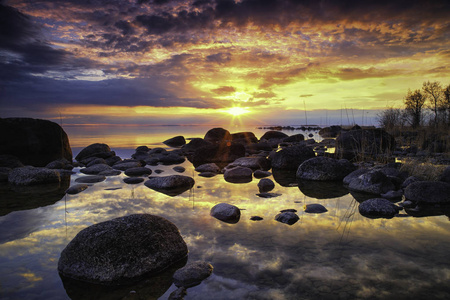 五颜六色的日落由湖与岩石海滩