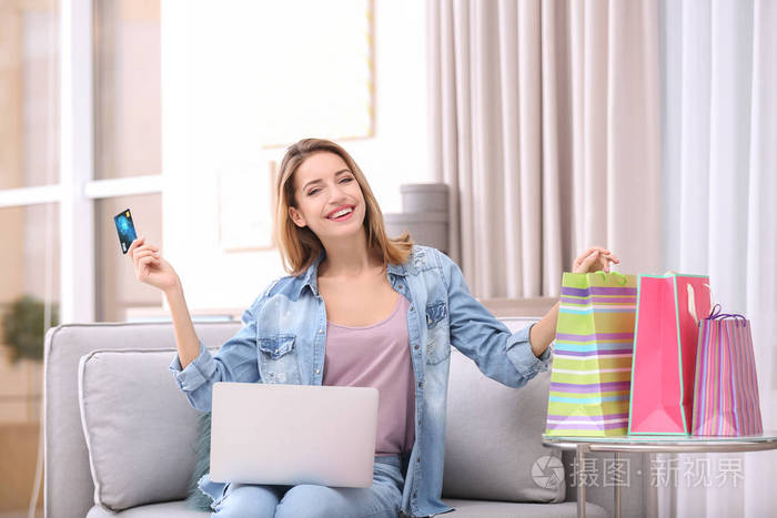 在家里有信用卡和笔记本电脑的漂亮女人.网上购物理念