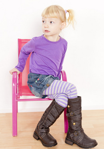 小女孩穿着靴子坐在椅子上