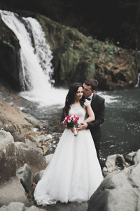 新婚夫妇在爱接吻和拥抱附近岩石上亮丽的风景线