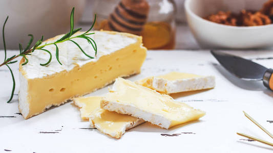 乳酪盘子配有饼干, 蜂蜜和坚果。乳酪在白色木材服务板上的白色纹理背景。开胃菜主题