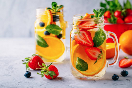 用橘子草莓蓝莓和薄荷糖注入排毒水。冰冷夏日鸡尾酒或柠檬水在玻璃梅森罐子