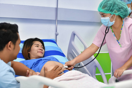 医生, 护士检查孕妇与听诊器在产科病房照片