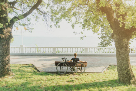 骑自行车的是在海岸线上的长凳上
