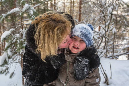 在一个下雪的冬天公园里和他的小儿子玩耍的年轻女子
