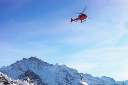红色直升机飞行在瑞士阿尔卑斯山 Mannlichen 在冬天