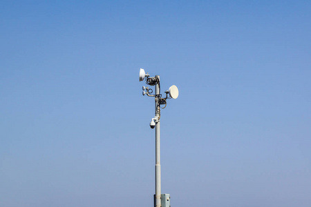 在阳光普照的蓝天的衬托的杆子上的监视摄像头 天线和通讯菜安全和卫星系统