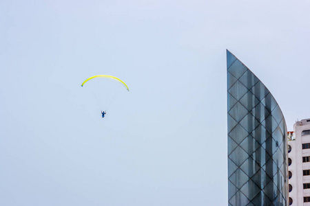 秘鲁利马上空的一座摩天大楼旁边的黄色滑翔伞