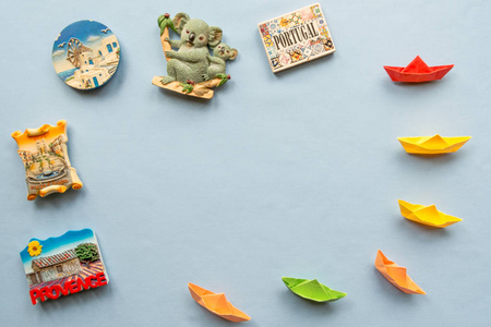 五颜六色的纸船和各种各样的纪念品磁铁从几个世界国家安排在蓝色背景