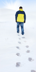 黄夹克行走在雪地，雪地上的脚印背后的男人