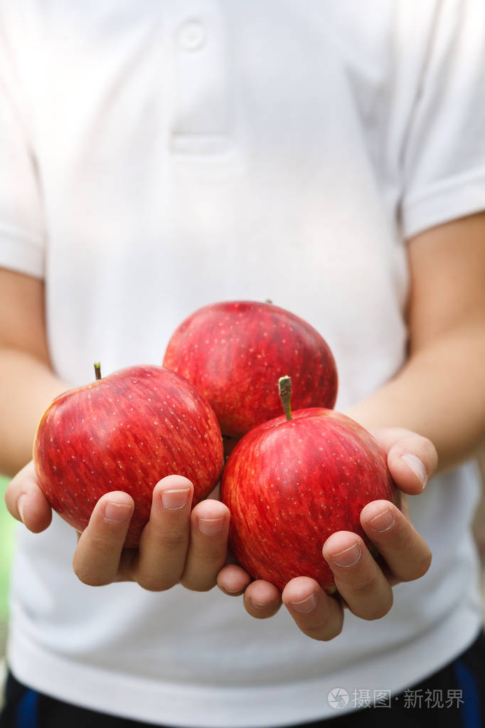 无法辨认的孩子手里拿着红苹果