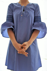 女孩苗条在长的蓝色时髦的衬衣与茂盛的袖子在白色背景下