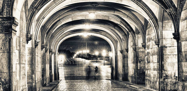 在古老的中世纪廊的夜晚行走的人们的影子