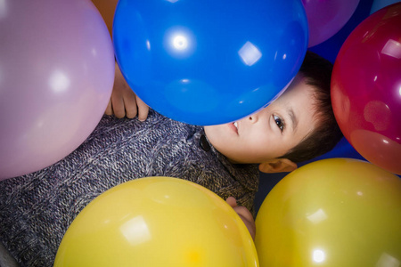 在生日聚会上玩五颜六色的气球, 微笑和喜悦的黑发男孩