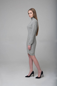 灰色针织连衣裙的年轻漂亮长发女性模特