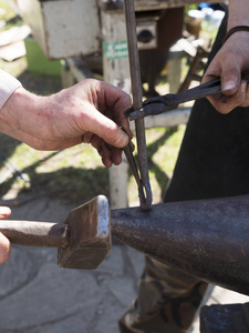 铁匠锻造锤铁在铁砧。工作手的细节。每日阳光