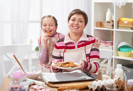 母亲和女儿烘烤饼干, 女孩吃曲奇饼, 家庭厨房内部, 健康食物概念
