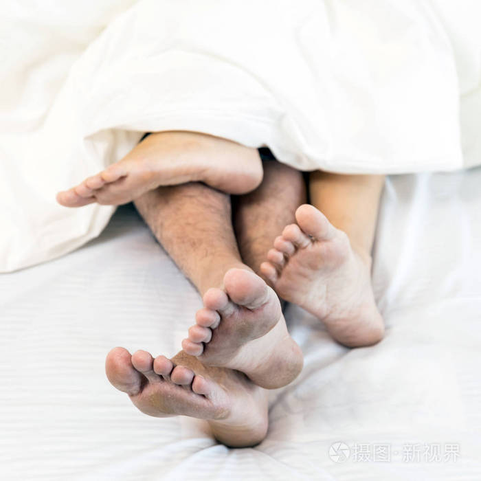 在床上的一对年轻情侣的近腿.现代生活方式概念