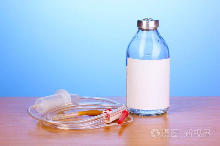 瓶静脉注射抗生素和设置在蓝色背景上的木桌上的塑料输液