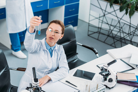 女性研究员在实验室中与同事一起寻找与试剂管的选择性聚焦