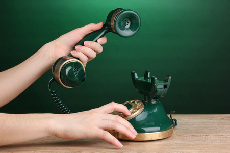 在绿色背景上的木桌上的复古电话拨号