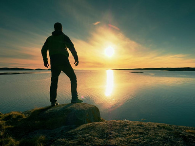 在海边的岩石悬崖上, 人们穿着户外衣服的剪影。日落时 Hikerthinking