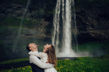 新婚夫妇抱着彩虹靠近瀑布图片