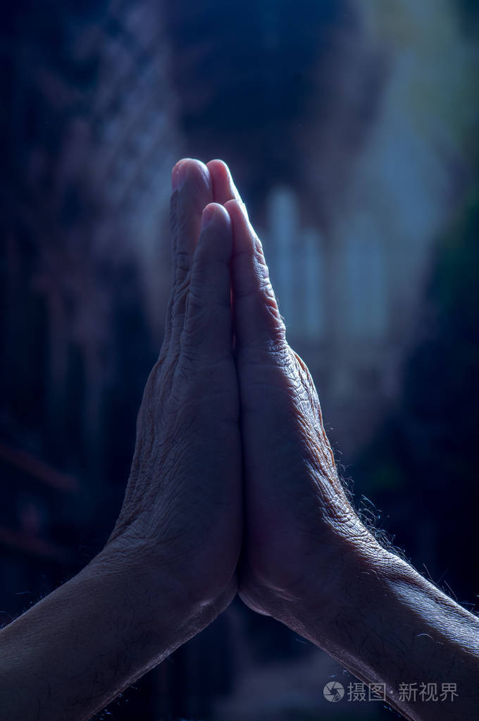 关闭祈祷的手黑暗的背景