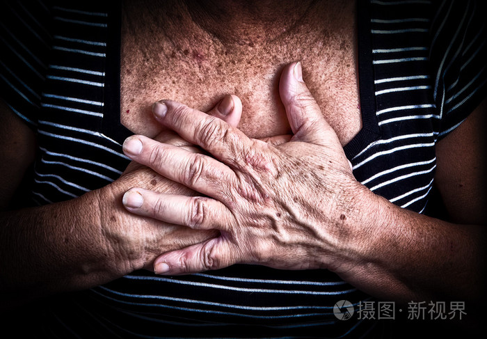 老年的妇女的手在她的胸口