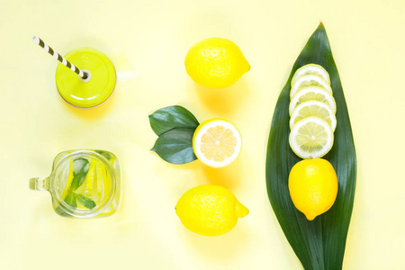 夏天柠檬成分为烹调排毒柠檬水与薄荷和冰在梅森罐子在黄色。热带概念。顶部视图。平躺