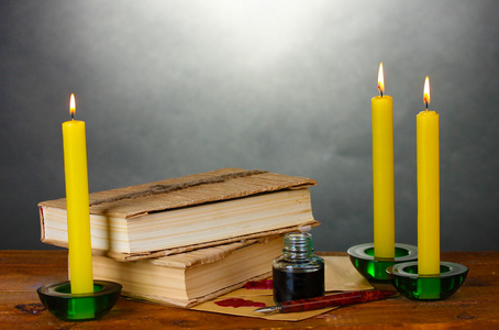 老书 卷轴 墨水钢笔墨水池和灰色的背景上的木桌上的蜡烛