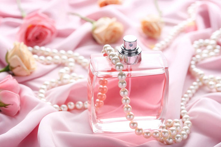香水瓶与玫瑰和珠缎背景照片