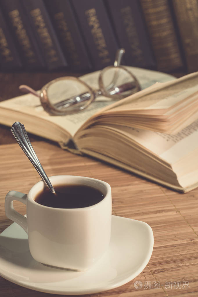 一杯咖啡和一本打开的书在桌上