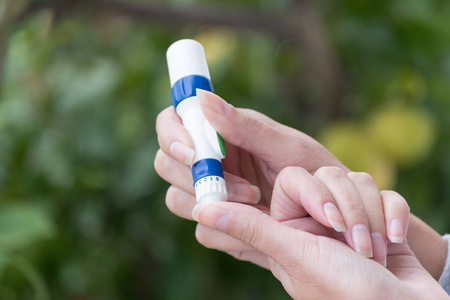 用手指柳叶刀对血糖表进行血糖检测的女性手特写