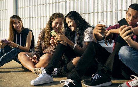 一群年轻的青少年朋友一起使用智能手机社交媒体的概念一起降温