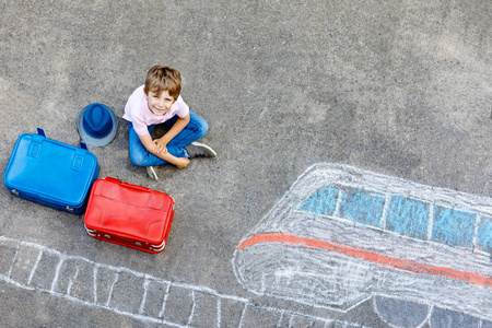 小家伙玩的愉快和快速火车画图用彩色粉笔在沥青上的男孩