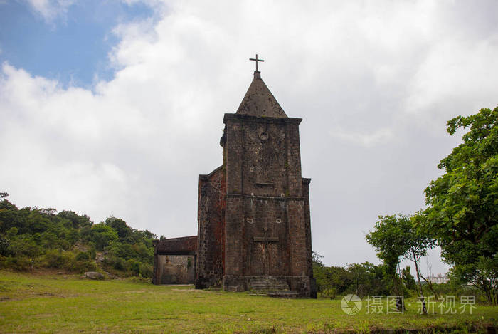 旧的废弃的教会在绿色领域。中世纪废墟在夏天风景。基督教寺庙从褐色石头