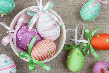 五颜六色的复活节彩蛋与丝带弓在麻布背景。复活节彩蛋快乐狩猎