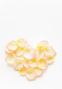 顶部视图平躺黄色和粉红色的茶叶玫瑰花瓣在心脏形状白色背景。爱情, 浪漫, 情人节的概念。文本空间