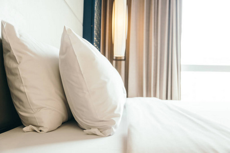 白色舒适的枕头在床装饰在旅馆卧室内部