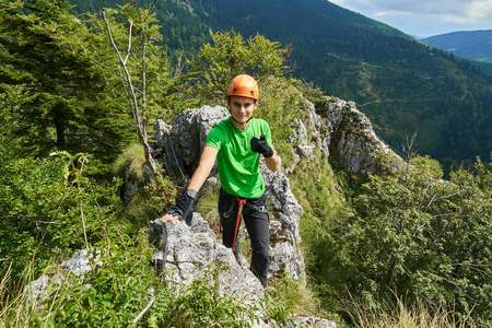 年轻男子穿着保护性登山装备在攀登时竖起大拇指标志