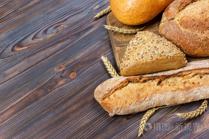 新鲜的面包和小麦在木头上。具有复制空间的顶部视图