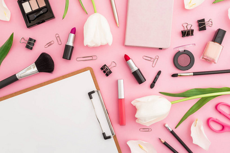 在粉红色的桌子上, 化妆品, 文具和郁金香的顶部视图