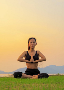 瑜伽女人是放松与美丽的日落背景上的