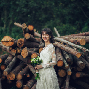 美丽的白种新娘在婚礼礼服与花束摆在前面的原木