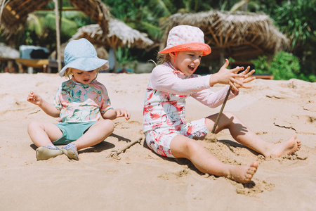 两个可爱的小妹妹在热带海滩玩沙子