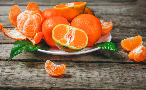 橘子 (官僚, clementines, 柑橘类水果) 与叶子在质朴的木背景与拷贝