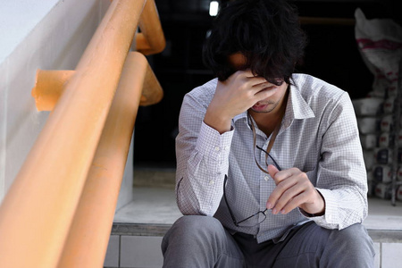 失意的年轻亚洲男人抚摸着头, 感到失望或疲惫.失业的生意人概念照片
