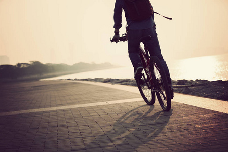 骑山地自行车的年轻女子在海边